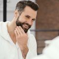 Homme souriant et se caressant la barbe avec la main , Saw Palmetto pour la perte de cheveux