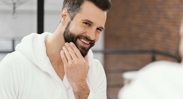 Homme souriant et se caressant la barbe avec la main , Saw Palmetto pour la perte de cheveux