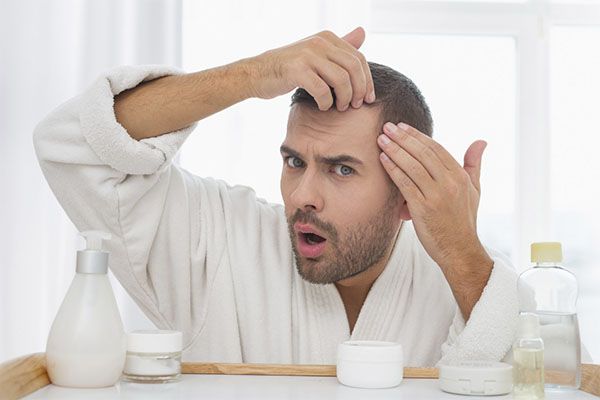 Saw Palmetto pour la perte de cheveux, Un homme surpris, car il souffre de perte de cheveux et que des crèmes capillaires l'entourent. 