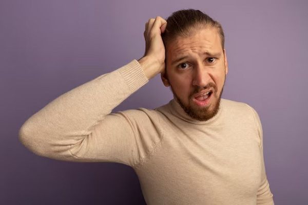 Jeune homme en col roulé beige confus avec une main sur la tête