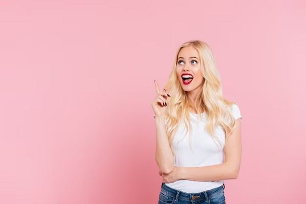 femme blonde surprise ayant une idée et levant les yeux sur le rose. Comment prendre soin des cheveux blonds