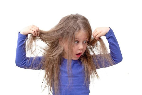 Petite fille mignonne tirant ses cheveux longs dans différentes directions. L'alopécie chez l'enfant, est-ce possible ?