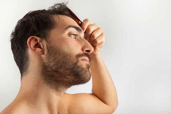 jeune bel homme se brossant les cheveux et semblant satisfait