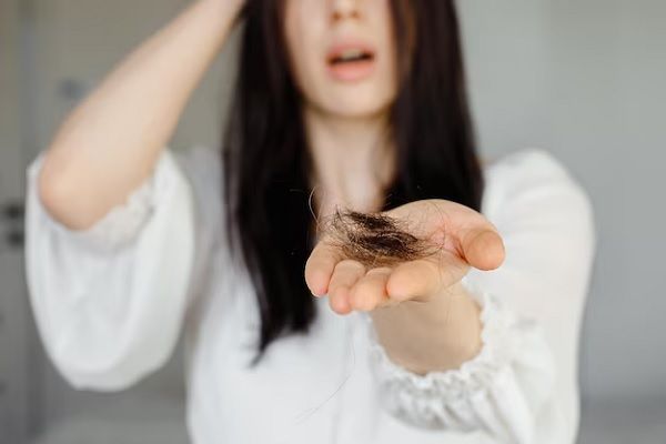 Gros plan d'une jeune femme souffrant de perte de cheveux et tenant dans sa main un bouquet de cheveux de sa tête.