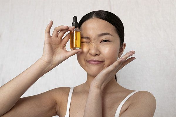 Vue de face d'une femme coréenne posant avec un sérum