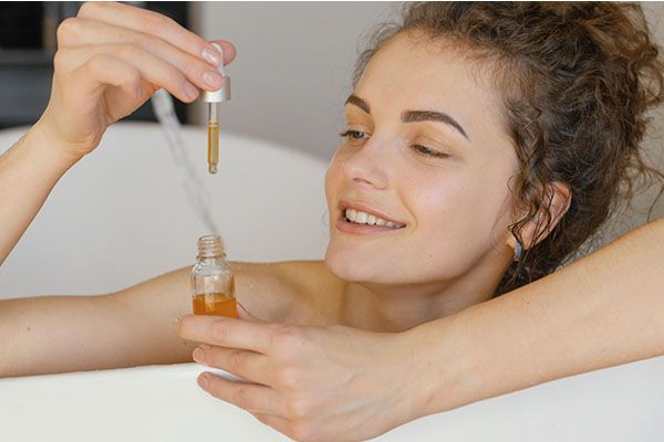 Femme se relaxant dans une baignoire avec un sérum. 