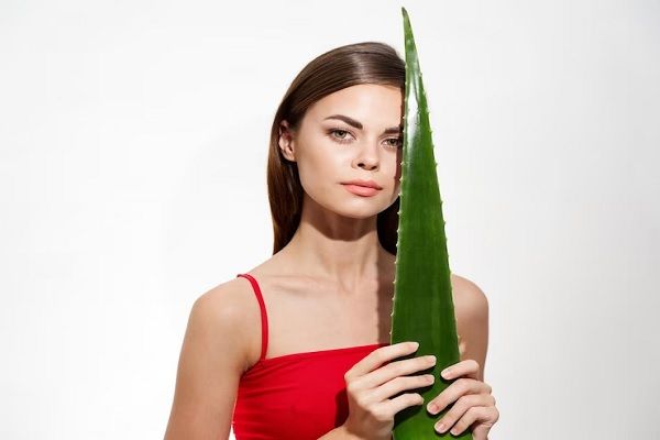 Portrait of young woman holding face against white background.