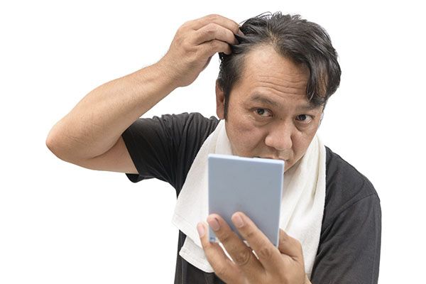 Il se regardait le cuir chevelu dans le miroir.