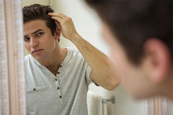 homme se regardant le cuir chevelu dans un miroir