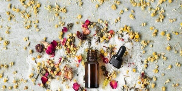 Fleurs avec bouteille de produits essentiels et petits déchets de fleurs. Les bienfaits du hair slugging, 