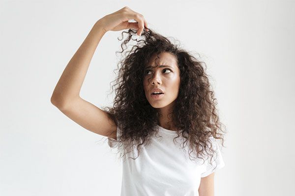 Belle femme aux cheveux bouclés se tenant les cheveux dans la main., La chute de cheveux et la pollution de l'air 