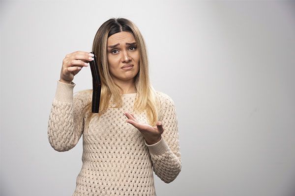 Femme à l'air inquiet avec un objet dans la main. 