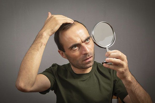 Il se regardait le cuir chevelu dans le miroir.