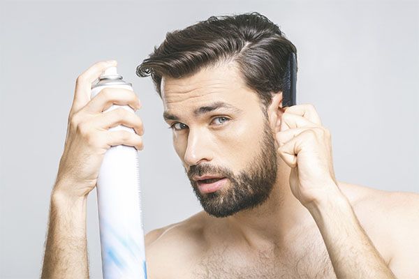 Homme appliquant de la crème capillaire sur ses cheveux 