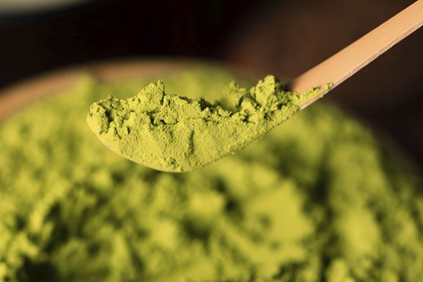 poudre verte sur le dessus d'une cuillère en bois 