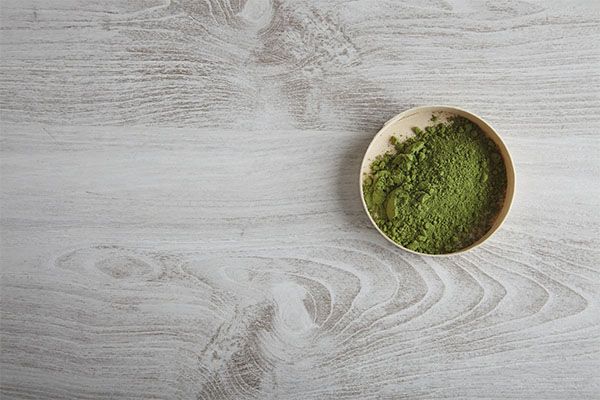 poudre verte sur le dessus d'une cuillère en bois 