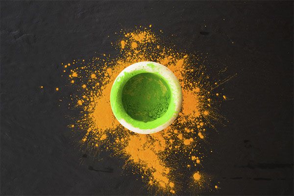 Poudre orange surmontée d'une poudre verte à l'intérieur d'un récipient noir. , Le henné est un produit que l'on trouve sous forme de poudre.