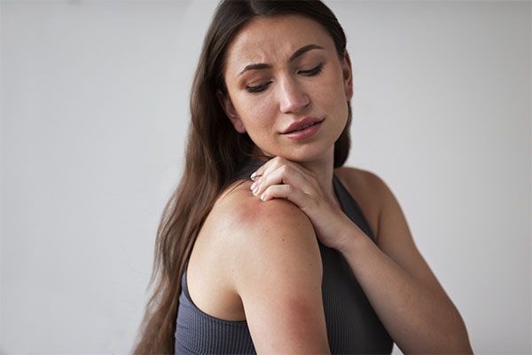  emme avec la main sur le dos avec une petite rougeur. Les différences entre l'eczéma et le psoriasis