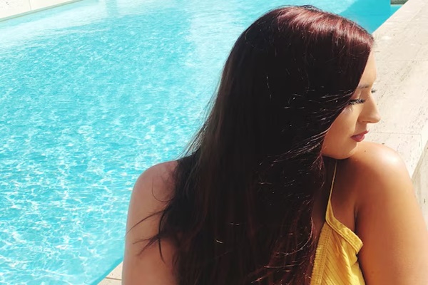 Jeune femme assise contre la piscine