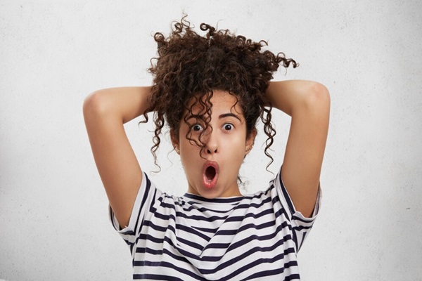 Une femme étonnée et surprise garde les mains derrière la tête