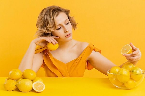 Femme assise à table avec un bol de citron