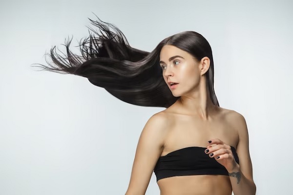 Beau modèle avec de longs cheveux bruns lisses et volants isolés sur fond de studio blanc