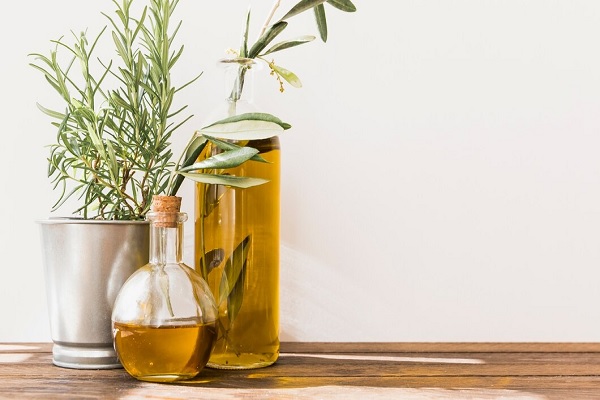 Romarin en pot avec des bouteilles d'huile d'olive sur une table en bois