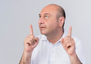 Homme d'affaires mature, impressionné, regardant de côté et pointant vers le haut, isolé sur fond blanc.