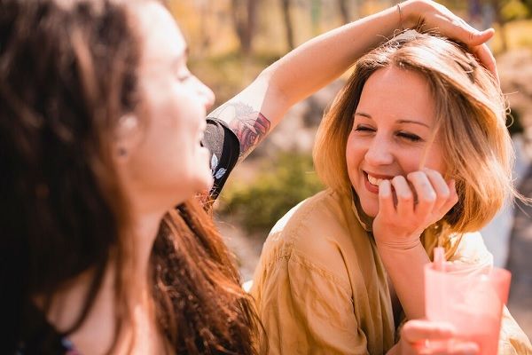 Femme touchant les cheveux d’un ami. Les soins des cheveux en été 