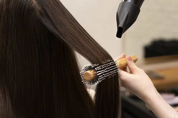 Cheveux d'une femme traités au sèche-cheveux. Avantages et inconvénients des lissages pour les cheveux