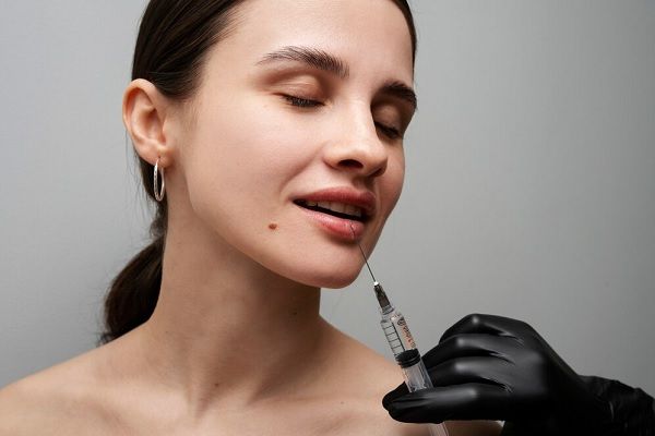Femme souriante recevant des produits de comblement pour les lèvres à la clinique