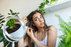 Portrait d'une jeune fille nerveuse et contrariée se passant les doigts dans les cheveux et pensant aux pellicules et à la perte de cheveux avec des émotions tristes. Concept de problème de perte de cheveux