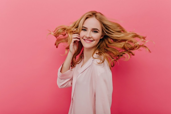 Femme pâle fascinante en pyjama rose clair exprimant le bonheur.