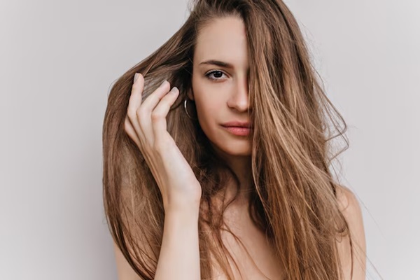 Photo en gros plan d'une adorable jeune femme touchant doucement ses cheveux.