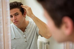 Homme vérifiant ses cheveux dans un miroir
