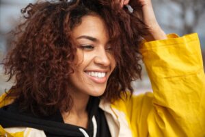 Jeune femme africaine heureuse aux cheveux bouclés et au manteau jaune