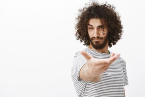 Portrait d'un bel homme barbu et frisé, sûr de lui, tendant la main vers l'extérieur.