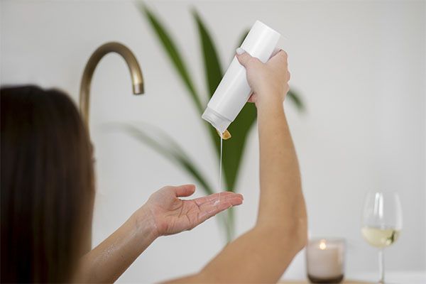 Femme utilisant un shampoing pour le traitement des cheveux, Shampooing chélateur, qu'est-ce que c'est et à quoi ça sert?