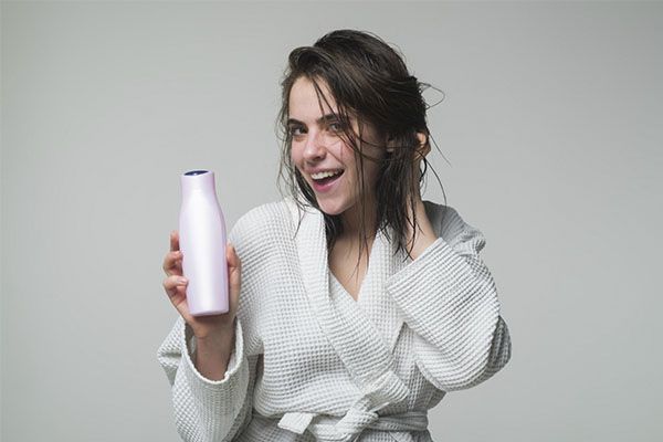 Femme heureuse montrant un shampouinage et tenant ses cheveux en place, meilleurs shampooings pour l'alopécie androgénétique 