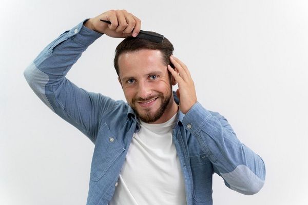 Mâle adulte se brossant les cheveux. Quelle est la relation entre la greffe de cheveux et le bonheur 