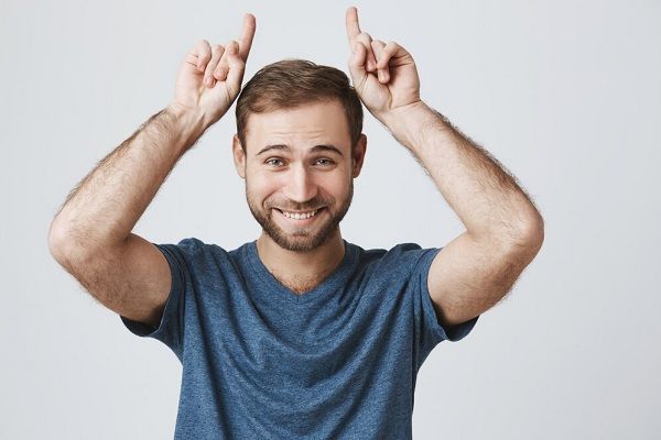 Bel homme heureux faisant des cornes de diable au-dessus de la tête