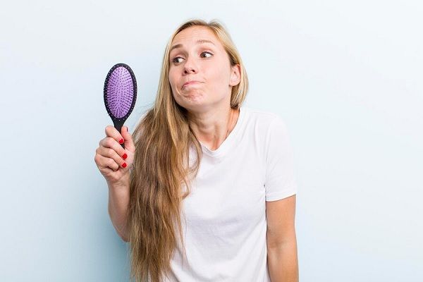 Jolie femme blonde avec un peigne. Perte de cheveux chez les femmes?