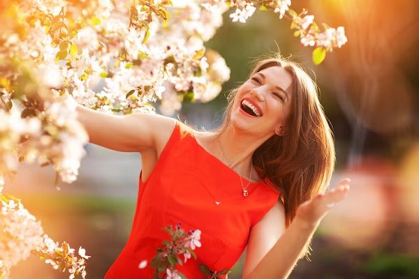Belle jeune femme brune debout près d'un arbre en fleurs.