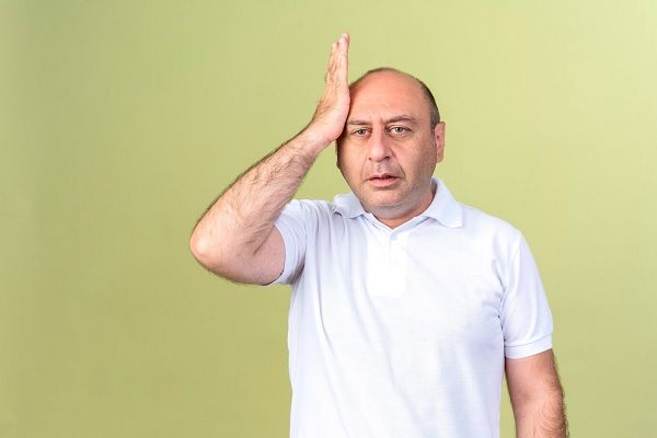Homme mûr mécontent mettant la main sur la tête isolée sur un mur vert olive.
La santé mentale affecte les cheveux.