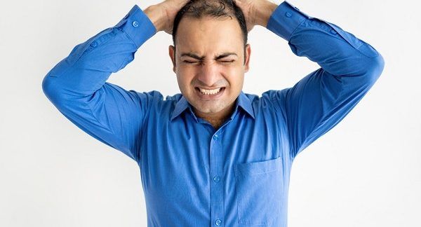 Portrait d'un homme d'affaires de taille moyenne qui pleure, tenant la tête dans les mains. La santé mentale affecte les cheveux.