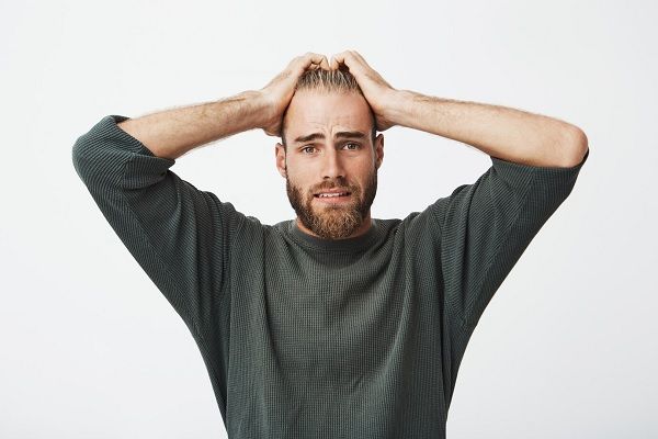 Malheureux jeune suédois avec barbe tenant la main sur la tête avec une expression effrayée.
La santé mentale affecte les cheveux.
