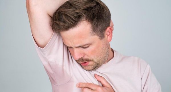 Transpiration excessive - Un homme blond remarque une grosse tache de sueur sous ses aisselles