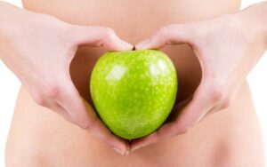 Détail des mains d'une femme tenant une pomme verte. Comment améliorer votre santé digestive