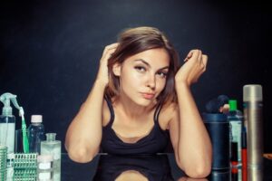 Belle femme après s'être maquillée. Belle fille se regardant dans le miroir. Concept de matin, de maquillage et d'émotions humaines. Modèle caucasien au studio. débarrasser des pellicules chez les femmes